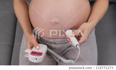 Close-up of a pregnant woman's belly using a home doppler. Blank screen. Close-up of a pregnant woman's belly using a home doppler. Blank screen. 118772273