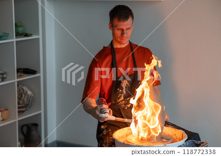 A potter burns a jug with a gas burner on a potter's wheel.  118772338