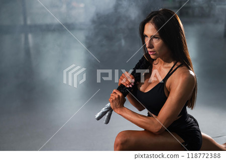 Caucasian woman holds the ropes and does a lunge in the exercise machine. Caucasian woman holds the ropes and does a lunge in the exercise machine. 118772388