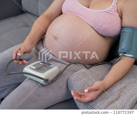 Close-up of the belly of a pregnant woman measuring blood pressure with a tonometer. Hypotension.  118772397