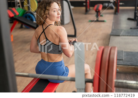 Middle-aged woman sitting on a bench in the gym. Middle-aged woman sitting on a bench in the gym. 118772419