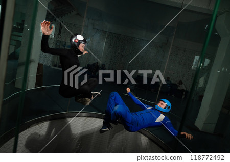 A man and a woman enjoy flying together in a wind tunnel. Free fall simulator 118772492