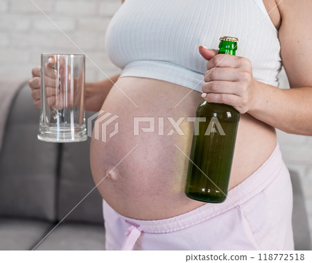 Pregnant woman holding glass and bottle of beer. Pregnant woman holding glass and bottle of beer. 118772518