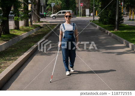 Blind pregnant woman walking down the street with a cane.  118772555