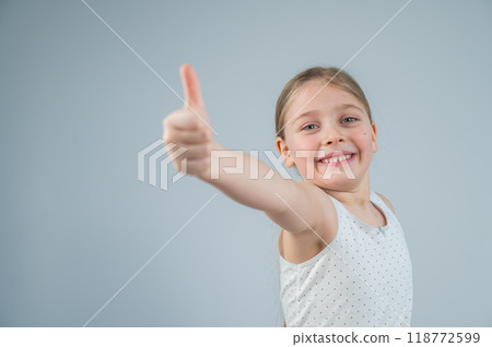 Caucasian 6 year old girl showing thumb up against white background. Caucasian 6 year old girl showing thumb up against white background. 118772599
