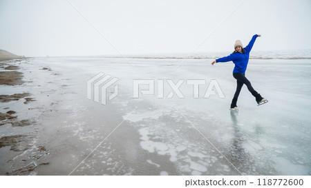 Caucasian woman in a blue sweater is skating on a frozen lake. The figure skater performs the program. Caucasian woman in a blue sweater is skating on a frozen lake. The figure skater performs the program. 118772600