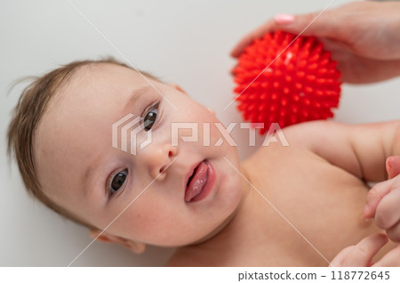 A doctor gives a baby a shoulder massage using a ball. A doctor gives a baby a shoulder massage using a ball. 118772645