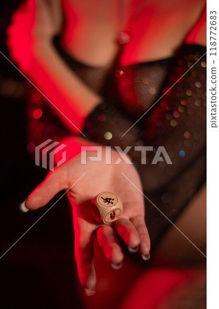 Seductive woman dressed in erotic fishnet holding dice with sex positions. Vertical photo. Seductive woman dressed in erotic fishnet holding dice with sex positions. Vertical photo. 118772683