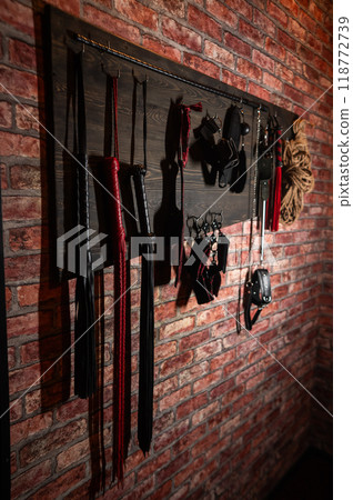 A set of BDSM equipment hanging on the wall. Vertical photo. A set of BDSM equipment hanging on the wall. Vertical photo. 118772739