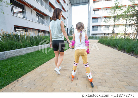 Mother helps daughter learn to roller skate.  118772775