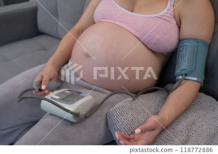 Close-up of the belly of a pregnant woman measuring blood pressure with a tonometer. Hypotension.  118772886