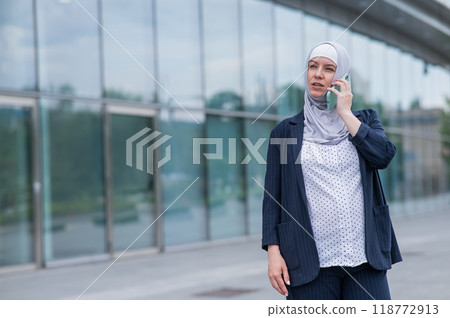Business woman in hijab and suit talking on smartphone. Business woman in hijab and suit talking on smartphone. 118772913