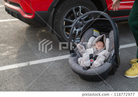 A Caucasian woman puts a child seat with a newborn baby in the car. Quick fastener.  118772977