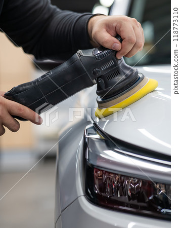 Process of polishing white car hood surface using orbital polishing machine. . Vertical photo.  118773110