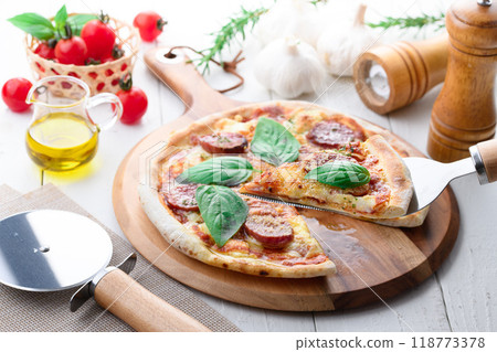 Italian pizza topped with plenty of salami and basil Italian pizza topped with plenty of salami and basil 118773378