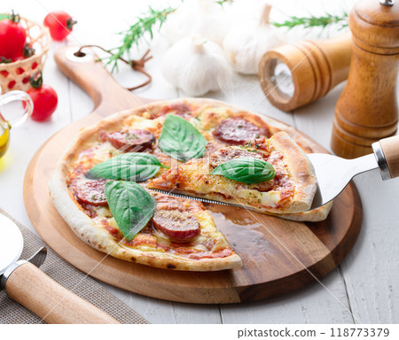 Italian pizza topped with plenty of salami and basil Italian pizza topped with plenty of salami and basil 118773379