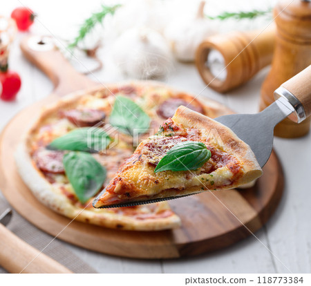 Italian pizza topped with plenty of salami and basil Italian pizza topped with plenty of salami and basil 118773384