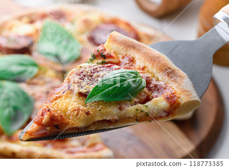 Italian pizza topped with plenty of salami and basil Italian pizza topped with plenty of salami and basil 118773385