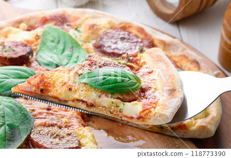 Italian pizza topped with plenty of salami and basil 118773390