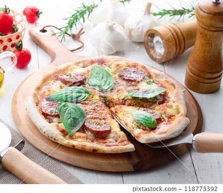 Italian pizza topped with plenty of salami and basil 118773392