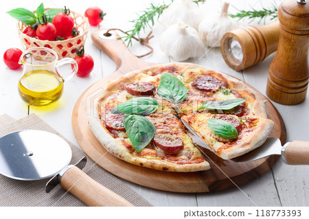 Italian pizza topped with plenty of salami and basil Italian pizza topped with plenty of salami and basil 118773393