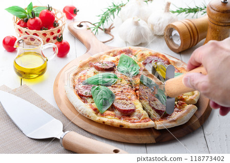 Italian pizza topped with plenty of salami and basil Italian pizza topped with plenty of salami and basil 118773402