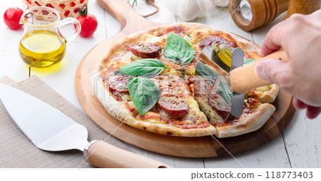 Italian pizza topped with plenty of salami and basil 118773403