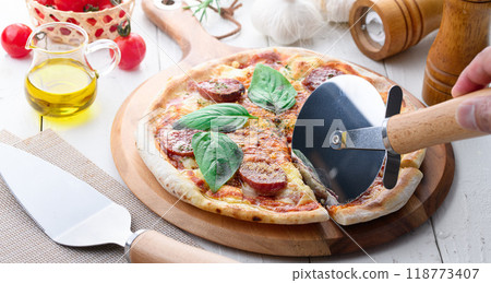 Italian pizza topped with plenty of salami and basil Italian pizza topped with plenty of salami and basil 118773407