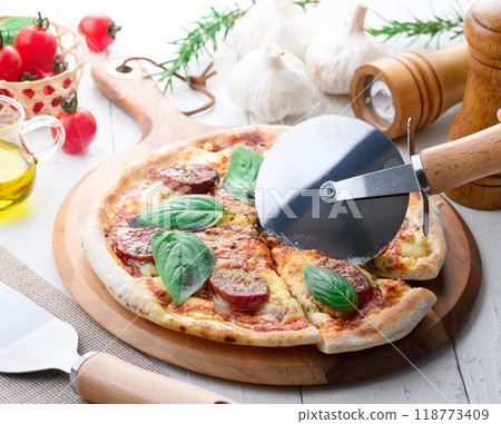 Italian pizza topped with plenty of salami and basil 118773409