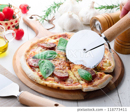 Italian pizza topped with plenty of salami and basil Italian pizza topped with plenty of salami and basil 118773411