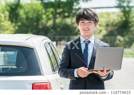 A young Asian man who is a car dealer appraiser/salesman assessing a car A young Asian man who is a car dealer appraiser/salesman assessing a car 118774635