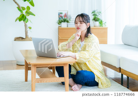 A young woman thinking while using a laptop at home 118774666