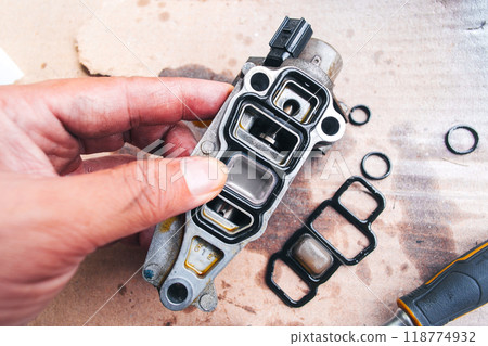 A mechanic is replacing a worn out rubber seal to repair a car engine part 118774932