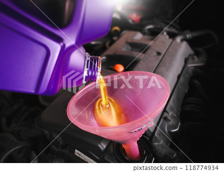 Engine oil is poured into the funnel by car mechanic for lubricating the engine 118774934