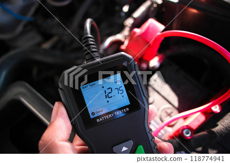 Battery voltage tester in a auto mechanic hand 118774941