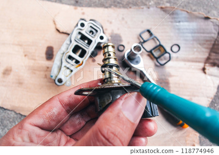 A mechanic is replacing a worn out rubber seal to repair a car engine part 118774946