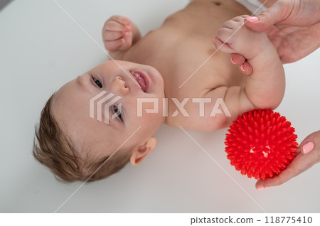 A doctor gives a baby a shoulder massage using a ball. A doctor gives a baby a shoulder massage using a ball. 118775410