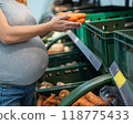 Pregnant woman buys carrots in the store.  118775433