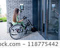 A woman in a wheelchair with an assistive device for manual control enters the entrance. Electric hand bike. 118775442