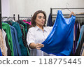 A fat woman chooses clothes in a plus size store.  118775445