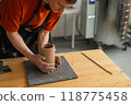 Close-up of a man's hands making a patterned cylinder out of clay.  118775458