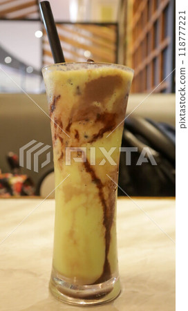 A glass of avocado juice with chocolate chips and ice cream topping on the table. A glass of avocado juice with chocolate chips and ice cream topping on the table. 118777221