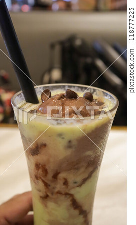 A glass of avocado juice with chocolate chips and ice cream topping on the table. A glass of avocado juice with chocolate chips and ice cream topping on the table. 118777225