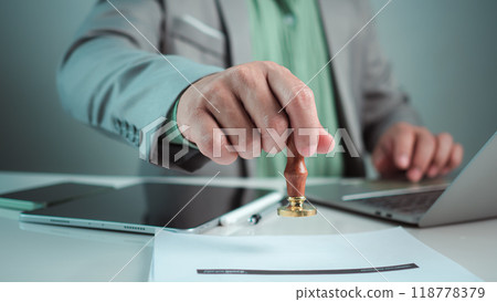 Businessman hand stamping with approved stamp on text approved document at desk, Validates and manages business documents and agreements, Approval stamp, Signing on business partner paper to success. Businessman hand stamping with approved stamp on text approved document at desk, Validates and manages business documents and agreements, Approval stamp, Signing on business partner paper to success. 118778379
