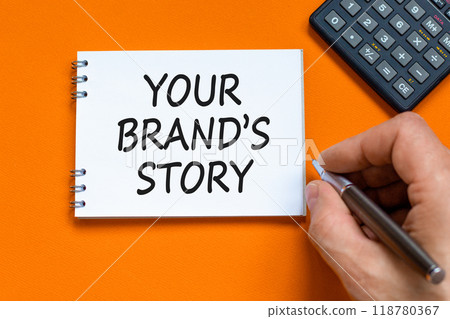 Branding and your brand story symbol. Concept words Your brands story on beautiful white note. Beautiful orange background. Businessman hand. Business branding your brand story concept. Copy space. 118780367