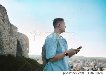Travel, map and Caucasian man pointing in city for adventure by the phone on the top of mountain, holiday or directions in MIrow Castle, Poland. Tourist, young male with document for location, search 118780692