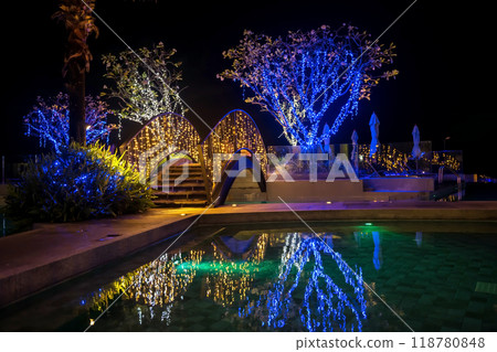 bridge and trees light up decor at swimming pool at night 118780848