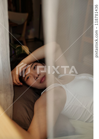 Woman with hangover resting on bed 118781436