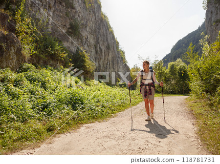 A hiker enjoying a beautiful scenic trail while using walking poles amidst natures beauty 118781731