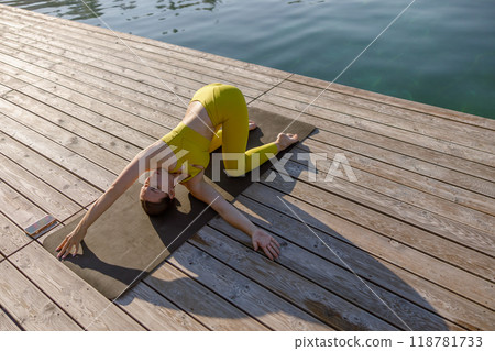 Engaging in a serene Yoga Pose by Waters Edge promotes tranquility, harmony and balance 118781733